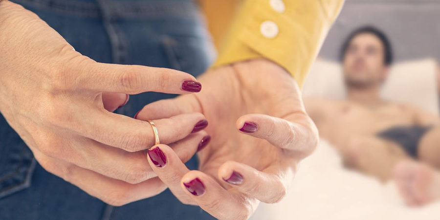 Woman cheating on her husband and removing her wedding ring behind her back