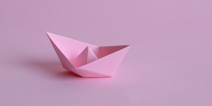 Oragami boat folded using pink paper designed to resemble a clitoris