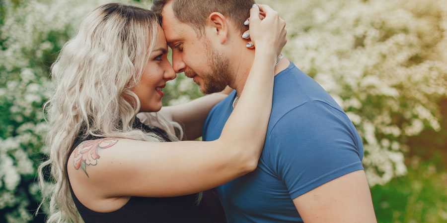 Sexy blonde woman with a shoulder tattoo looking into her lover's eyes