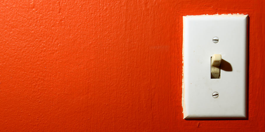 Light switch on a brightly painted orange wall 