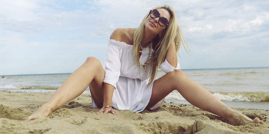 Very attractive woman with long blonde hair sitting on the beach looking like she's having fun