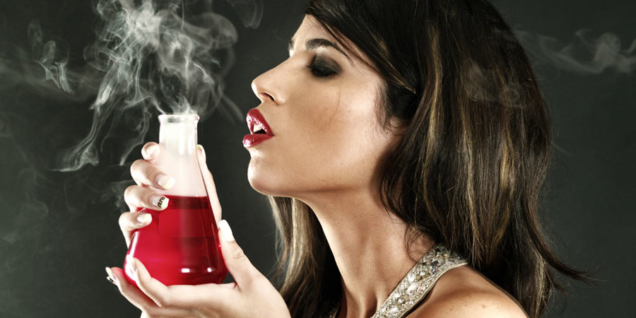 Attractive brunette woman smelling an aphrodisiac in a glass laboratory beaker